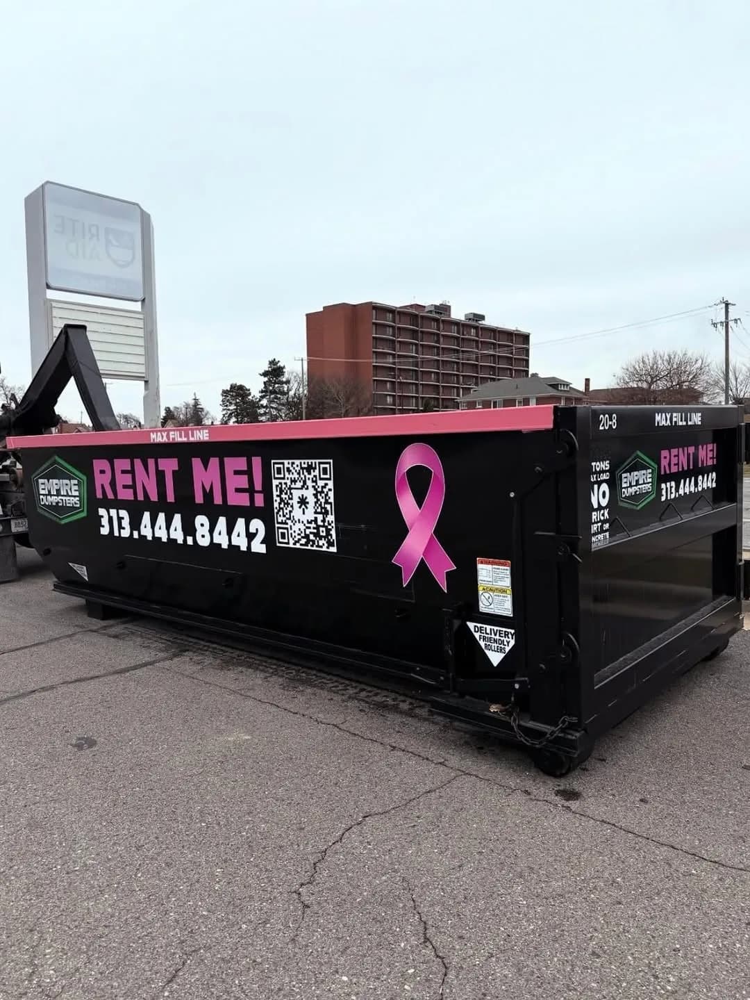 Black Empire Dumpsters 20 yard roll-off dumpster with a pink top rail, pink Rent Me lettering and a large pink breast cancer awareness ribbon