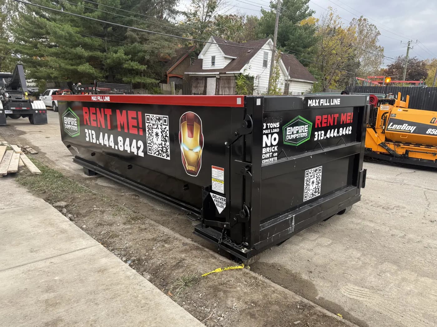 Two Empire Dumpsters roll-off containers, one wrapped with an Iron Man helmet graphic