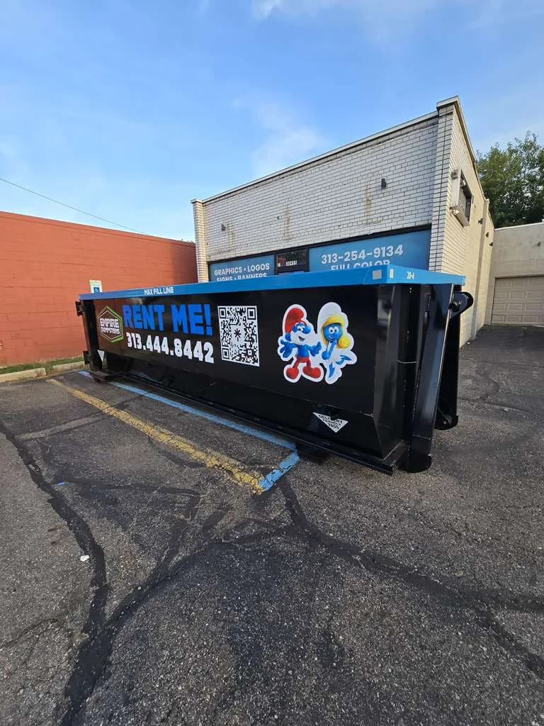 Black Empire Dumpsters roll-off with a blue rail and Smurf and Smurfette graphics